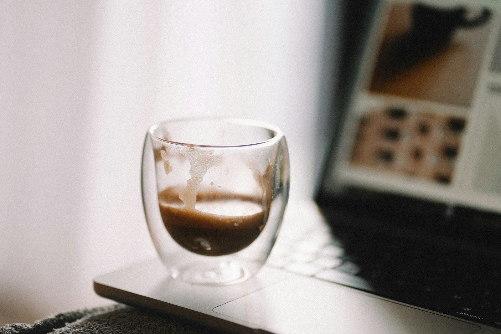 A glass of liquid sitting on top of a laptop computer